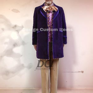 Puede incluir: Un abrigo largo de terciopelo morado con ribetes morados, usado sobre una camisa estampada y una gran pajarita. El atuendo incluye pantalones color beige. El texto "Design Custom Items" es visible.