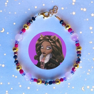 May include: A colorful beaded bracelet with gold, black, purple, and pink beads. The bracelet has a clasp closure and features a charm of a cartoon girl with brown hair and a white fur collar.