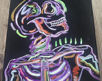 May include: A neon-coloured painting of a skeleton on a black background. The skeleton is outlined in bright colours, including purple, green, orange, and white. The skull is facing to the right, and the ribs are visible.