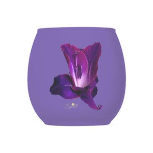 May include: Purple glass candle holder with a purple flower design. The candle holder has a rounded shape and a smooth surface. The flower design is centered on the front of the candle holder.