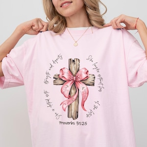 She Is Bible Verse Shirt, Proverbs 31:25 Shirt, Christian Gifts,Coquette Bow Cross Sweatshirt, Faith Coquette Sweater, Christian Girl Shirt