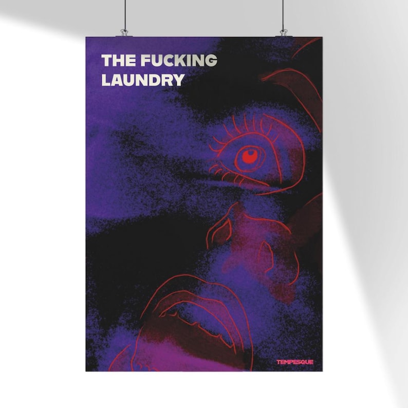 Op de afbeelding: Poster met de tekst "THE FUCKING LAUNDRY" in het wit, boven een gestileerde illustratie in rood en paars. De illustratie toont een gezicht met een oog en een mond. De achtergrond is een mix van zwart, paars en rood.