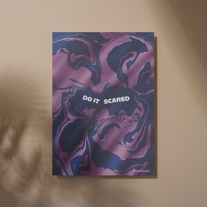 May include: A rectangular art print with a swirling, marbled design in shades of purple and navy blue. The words "DO IT SCARED" are in white, centered on the print. The print has a glossy finish and is displayed against a neutral background.