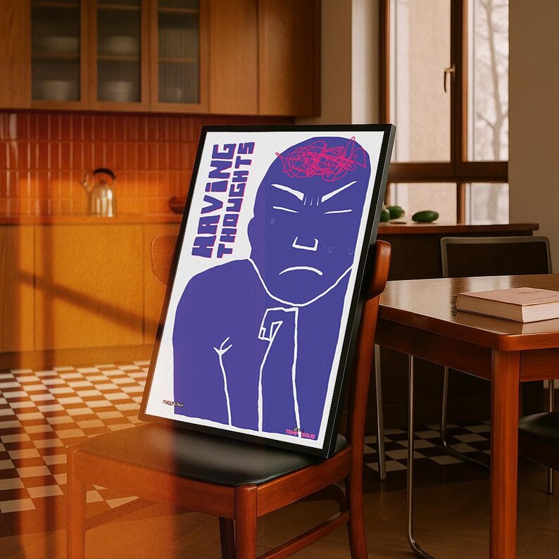 May include: A framed art print featuring a blue illustration of a person with the words "HAVING THOUGHTS" in white. The person has a furrowed brow and a pink brain illustration. The print is displayed on a wooden chair.