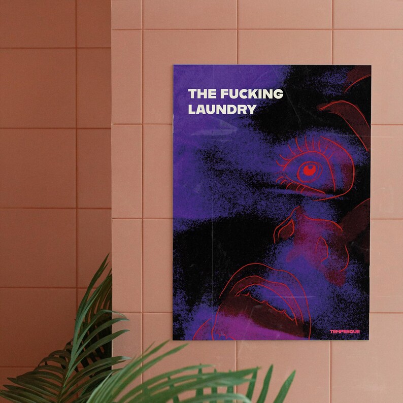 Op de afbeelding: Een poster met de tekst "THE FUCKING LAUNDRY" in witte letters. Het kunstwerk toont een paars en zwart abstract ontwerp met rode contouren van een gezicht. De poster hangt aan een roze betegelde muur.