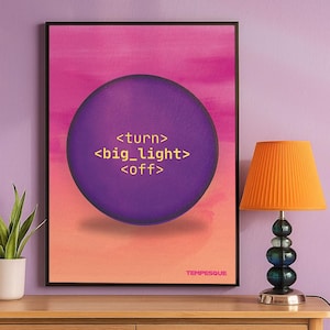 Può includere: Una stampa artistica incorniciata con un cerchio viola e il testo "<turn> <big_light> <off>" su uno sfondo sfumato rosa e arancione. Una lampada arancione con paralume plissettato è su una superficie di legno.