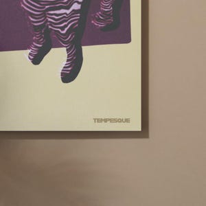 May include: A print with a beige background and a dark purple abstract design. The word "TEMPESQUE" is printed in a light grey color at the bottom of the print.