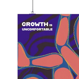 May include: A poster with the text "GROWTH IS UNCOMFORTABLE" in white letters on a dark blue background. The poster features abstract shapes in shades of red and blue with yellow outlines.