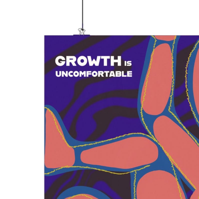 May include: A poster with the text "GROWTH IS UNCOMFORTABLE" in white letters on a dark blue background. The poster features abstract shapes in shades of red and blue with yellow outlines.