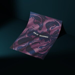 May include: A poster with a swirling pattern in shades of purple and navy blue. The text "DO IT SCARED" is printed in white across the top. The poster is leaning against a dark teal wall.