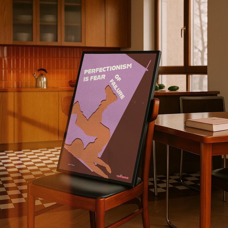K&ouml;nnte beinhalten: Ein gerahmtes Poster mit dem Text "PERFECTIONISM IS FEAR OF FAILURE" in Wei&szlig;. Das Poster zeigt eine Illustration einer st&uuml;rzenden Person mit einem lila und braunen Farbschema. Das Poster ist auf einem Holzstuhl aufgestellt.