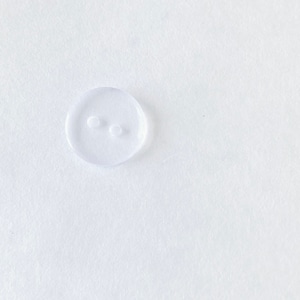 May include: A clear plastic button with two holes.