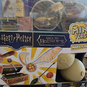 May include: A Harry Potter-themed Mini Verse set featuring miniature replicas of iconic items. The set includes a golden snitch, a broom, treasure chests, and a bottle with the Hogwarts crest. The packaging reads "Back to Hogwarts" and "Make it Mini".