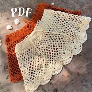 Puede incluir: Se muestran dos faldas de ganchillo, una en naranja cálido y otra en crema. Las faldas tienen un diseño de red con un borde festoneado. La palabra "PDF" es visible en la esquina superior izquierda.