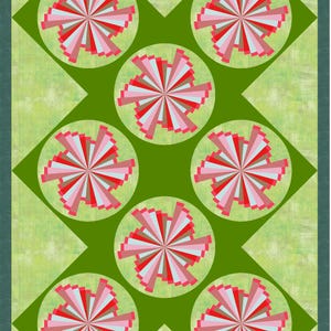 May include: A rectangular quilt featuring a light green textured background with a dark green border. The design consists of seven circular motifs arranged in a diamond pattern, each containing a radial burst of pink, red, and white fabric strips.