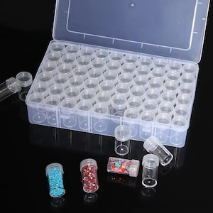 May include: A clear plastic storage box with a hinged lid containing numerous small, empty, cylindrical vials. Several additional empty vials and a few vials filled with colorful, tiny decorative beads are arranged in front of the container.