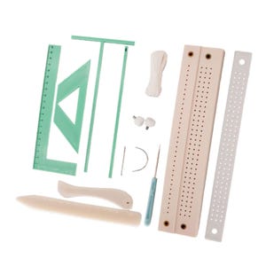 Könnte beinhalten: Ein Buchbindewerkzeug-Set bestehend aus einem hellgrünen T-Lineal, einem Dreieckslineal, einem geraden Lineal, zwei beigen perforierten Ausrichtungsbrettern, einem weißen Lineal, einem Falzbein, einem Rillwerkzeug, weißem Garn, zwei Nadeln und zwei Schrauben.