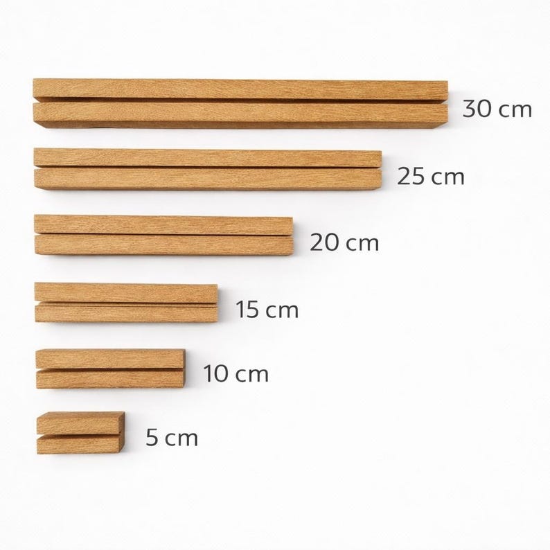 May include: A selection of wooden magnetic poster hangers in different lengths: 30 cm, 25 cm, 20 cm, 15 cm, 10 cm, and 5 cm. The light brown wooden hangers are designed to display posters or artwork.