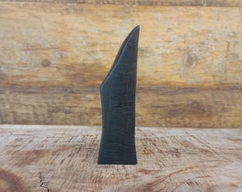 以下が含まれることがあります： 高く、細長く、抽象的な形をした、濃い色の木彫り。彫刻は滑らかで磨かれた表面と尖った頂上を持っています。