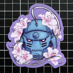 May include: A sticker depicting a blue helmet with red eyes, framed by pink and white flowers, on a purple background. The design is cartoon-like and set against a black grid.