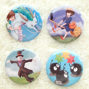 May include: Four round buttons featuring different images from the animated film Studio Ghibli. The first button depicts a blue background with a white dragon and a girl with brown hair. The second button shows a blue background with a girl with brown hair riding a broomstick with a black cat. The third button features a blue background with a black and white illustration of a scarecrow. The fourth button has a blue background with three fluffy white creatures with black eyes.