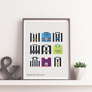 Op de afbeelding: Een ingelijste print met negen gestileerde voetbalshirts in verschillende ontwerpen. De shirts zijn voornamelijk zwart-wit, blauw en geel, met geometrische patronen en logo's. De zin "FRAME NOT INCLUDED" staat onderaan afgedrukt.