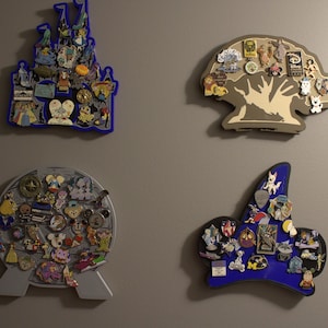 May include: Four decorative pin display boards in various shapes, including a castle, a tree, a globe, and a sorcerer's hat. Each board is filled with colorful pins, showcasing a collection of themed pins.