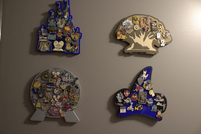 May include: Four decorative pin display boards in various shapes, including a castle, a tree, a globe, and a sorcerer's hat. Each board is filled with colorful pins, showcasing a collection of themed pins.