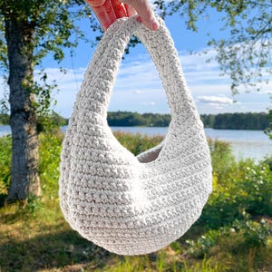Modern virkad axelväska med snygg rund design.