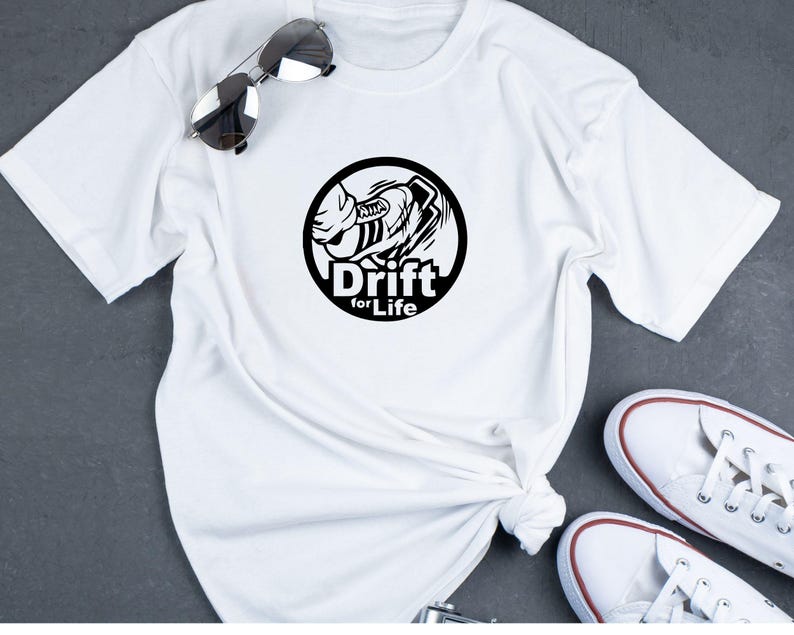 May include: White t-shirt with a black circular graphic featuring a stylized car and the words "Drift for Life." The shirt is paired with sunglasses and white sneakers.