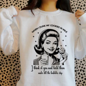May include: White sweatshirt with a black and white illustration of a woman dipping a cookie in milk. The text reads "WHEN I DUNK MY COOKIES IN MILK I think of you and hold them under till the bubbles stop."