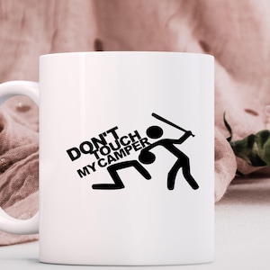 May include: White ceramic mug with a black graphic that reads "DON'T TOUCH MY CAMPER." The graphic depicts stick figures, one swinging a bat at another on the ground. The mug has a white handle.