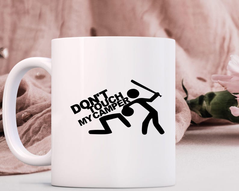 May include: White ceramic mug with a black graphic that reads "DON'T TOUCH MY CAMPER." The graphic depicts stick figures, one swinging a bat at another on the ground. The mug has a white handle.
