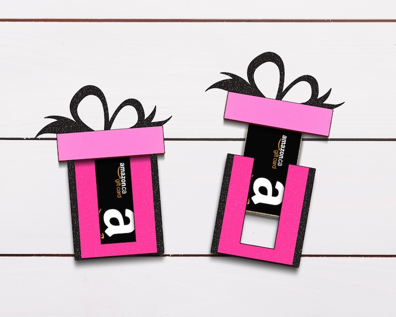 May include: Two pink gift boxes with black bows and a black and yellow Amazon gift card inside one of the boxes.