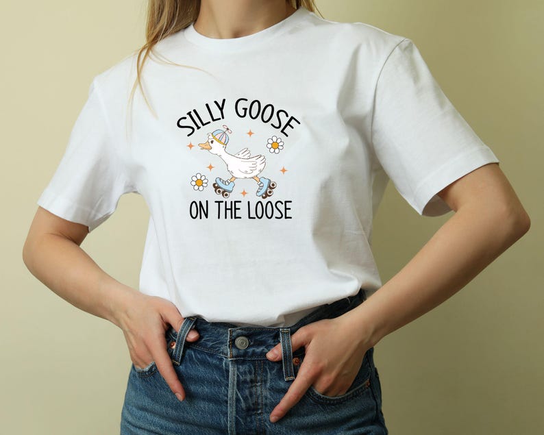 May include: White t-shirt with a cartoon goose on roller skates and the words "Silly Goose on the Loose." The design includes daisies and stars. The shirt is made of a soft, comfortable material.