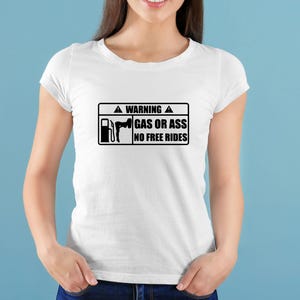 May include: White t-shirt with a black rectangular graphic. The graphic includes a gas pump and a silhouette of a person, along with the text "WARNING GAS OR ASS NO FREE RIDES". The shirt is a crew neck style.