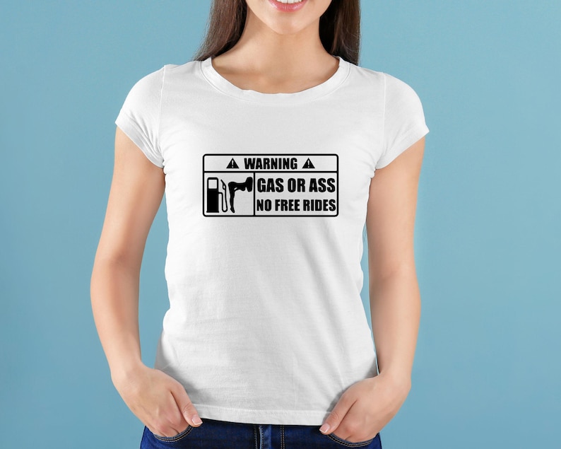 May include: White t-shirt with a black rectangular graphic. The graphic includes a gas pump and a silhouette of a person, along with the text "WARNING GAS OR ASS NO FREE RIDES". The shirt is a crew neck style.