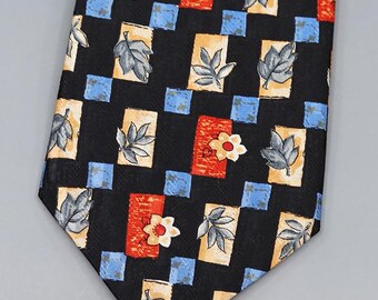 May include: Black necktie with a repeating pattern of leaves, flowers, and geometric shapes in shades of blue, orange, and beige. The tie is made of a smooth fabric and has a classic pointed end.