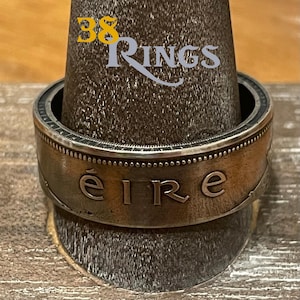 May include: A silver ring made from a repurposed Irish coin. The ring features the inscription "éire" on the band.