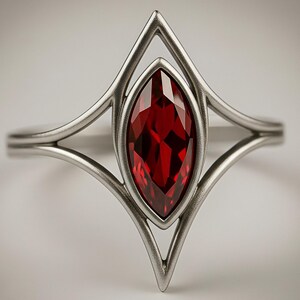 May include: A silver-toned ring featuring a central marquise-cut deep red gemstone. The metal band splits into two symmetrical, pointed arches that frame the stone, creating a geometric, elongated diamond-shaped setting with a smooth finish.