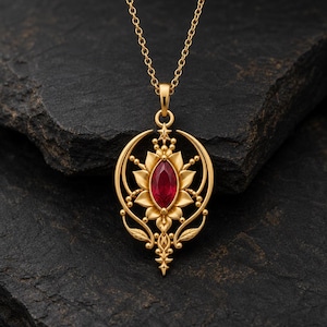 May include: A gold pendant necklace featuring a central marquise-cut red gemstone surrounded by a stylized floral and crescent moon frame. The intricate metalwork includes delicate leaf motifs and a small star accent at the top.