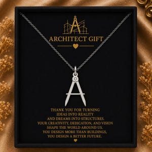 May include: Silver necklace with a compass pendant, presented in a black gift box. The box features the text "ARCHITECT GIFT" and a message about creativity and vision. The pendant is a stylized letter "A".
