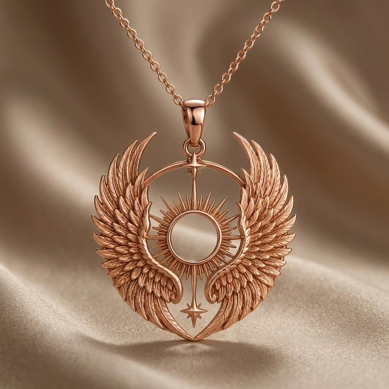 K&ouml;nnte beinhalten: Eine Halskette mit Anh&auml;nger aus Ros&eacute;gold, die ein detailliertes Design aus Fl&uuml;geln, einem Sonnenstrahl und einem Stern aufweist. Der Anh&auml;nger h&auml;ngt an einer zarten Kette. Die Halskette wird vor einem neutralen Hintergrund gezeigt.