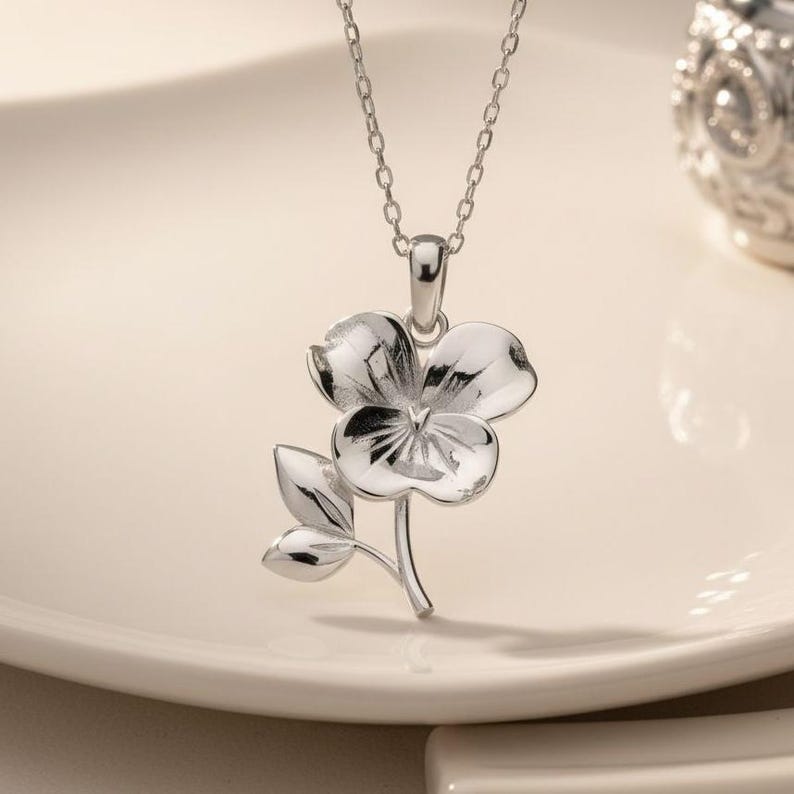 Violet birth flower necklace in 925 sterling silver featuring a delicate floral February symbol design. This handmade silver floral necklace represents loyalty, devotion, and emotional connection, making it a meaningful birthday gift for her. The violet flower pendant hangs from a fine cable chain with a minimalist, feminine style perfect for everyday wear or romantic occasions.