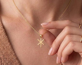 May include: A gold-toned necklace featuring a delicate chain and a pendant shaped like a six-pointed star or asterisk. The pendant has a smooth, polished finish and is suspended from a thin, matching gold-colored metal chain link necklace.