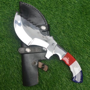 以下が含まれることがあります： 赤、白、青のハンドルが付いた銀色のナイフ。ナイフは湾曲した刃を持ち、黒い革製の鞘に入っています。