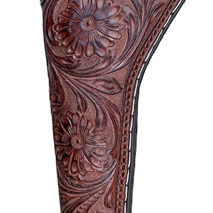 Può includere: Una fondina in pelle marrone con un'intricata lavorazione floreale. La fondina presenta un design decorativo con un bordo cucito e un cinturino in pelle. Il prodotto è progettato per contenere un'arma da fuoco.