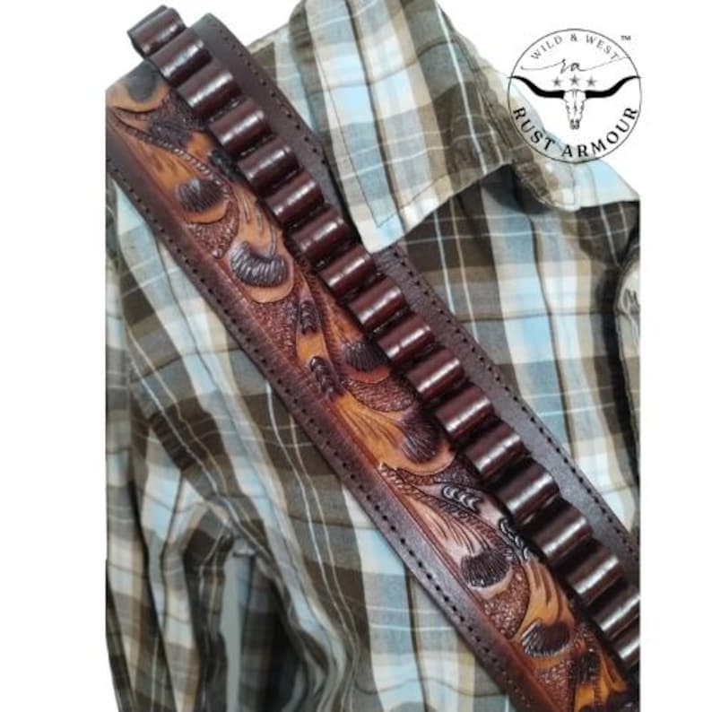 May include: A brown leather gun belt with carved floral patterns and bullet loops. The belt is worn over a checked shirt. The image includes a circular logo with the text "Wild & West Rust Armour".