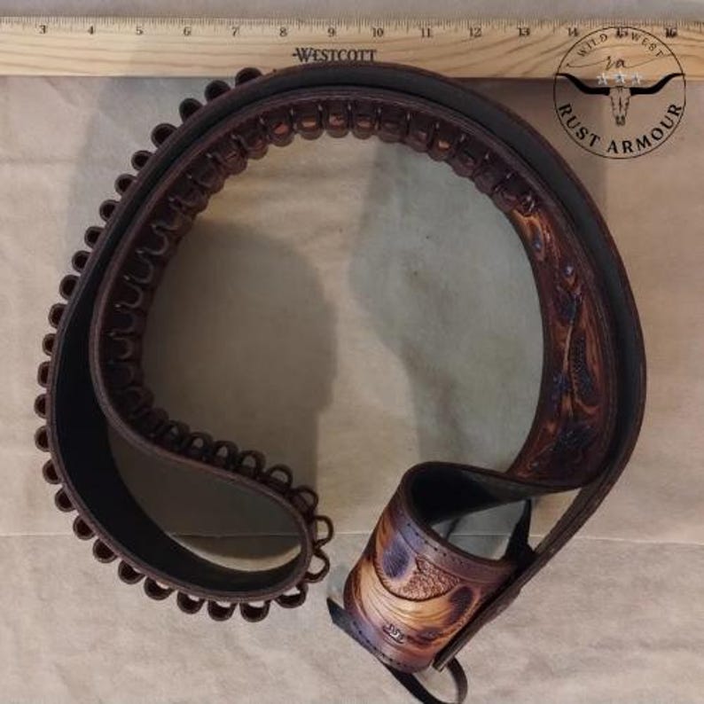 May include: A brown leather cartridge belt with decorative stitching and a carved design. The belt is designed to hold ammunition and features loops for cartridges. The belt is a western-style accessory.