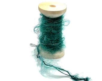 May include: A spool of teal green yarn with silver thread wrapped around a wooden bobbin.